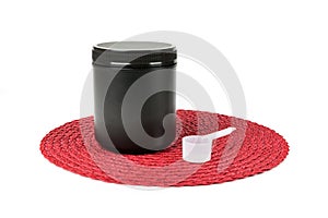 Black supplement tub with scoop on a red patterned background