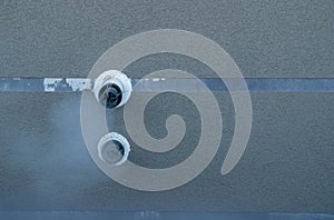 Black supply and exhaust outlets of heating gas boiler, mounted on facade of residential building, lined with decorative plaster