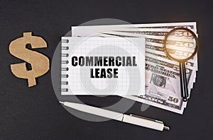 On a black surface are dollars, a pen and a notepad with the inscription - COMMERCIAL LEASE