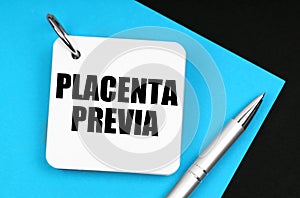 On the black surface lies blue paper, a pen and a notebook with the inscription - Placenta Previa photo