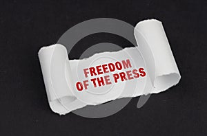 On a black surface lies a white twisted paper with the inscription - Freedom of the press