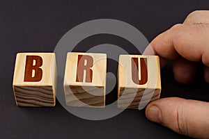 On a black surface, a man puts cubes with the inscription - BRU