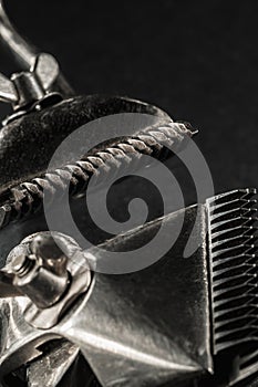 On a black surface are old barber tools.Two vintage manual hair clipper. black monochrome. Close-up. Barbershop background.