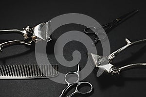 On a black surface are old barber tools. vintage manual hair clipper, comb, hairdressing scissors. black monochrome