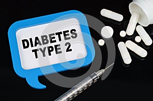 On a black surface, a syringe, pills and a blue frame with the inscription - DIABETES TYPE 2
