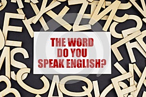 On a black surface are wooden letters and a business card with the inscription - THE WORD DO YOU SPEAK ENGLISH