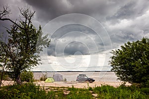 Black SUV with rooftop box near camping at the river