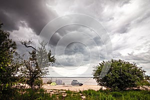 Black SUV with rooftop box near camping at the river