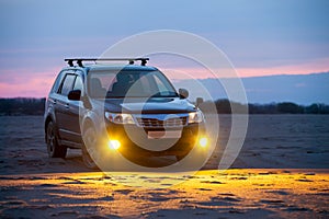 Black crossover at sandy beach at sunrise