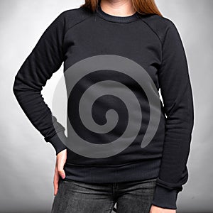 Black sweatshirt jacket with sleeves dressed on a girl on a gray background. Vertical orientation