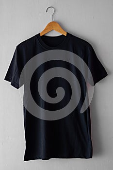 Black t-shirt on wood hanger isolated on grey grunge background