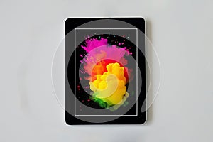 Black tablet used for the internet creating and communication with colorful splash of colors blend into each other