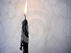 Black tall beeswax candle burning