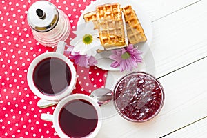 Black tea ceremony - a cup of tea, teapot, sugar, cakes, flowers on a red with white dots background