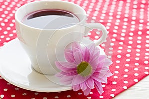 Black tea ceremony - a cup of tea, teapot, sugar, cakes, flowers on a red with white dots background