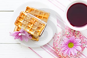 Black tea ceremony - a cup of tea, teapot, sugar, cakes, flowers on white wooden rustic background