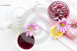 Black tea ceremony - a cup of tea, teapot, sugar, cakes, flowers on white wooden rustic background