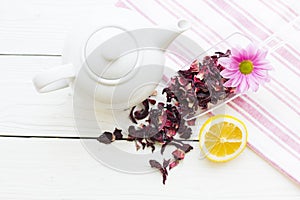 Black tea ceremony - a cup of tea, teapot, sugar, cakes, flowers on white wooden rustic background