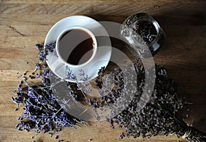 Black tea or coffee in a white cup on a board with dried herbs