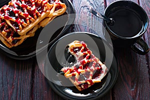 Black tea cup, black plate with cookies and biscuits