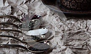 Black tea cup with golden spoons and green, black and carcade tea,