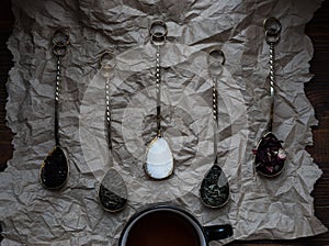 Black tea cup with golden spoons and green, black and carcade tea,