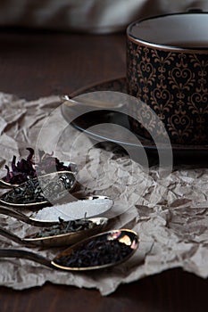 Black tea cup with golden spoons and green, black and carcade tea, photo