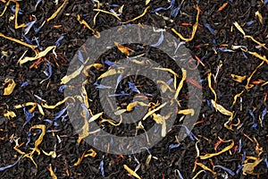 Black tea with dried flower leaves full frame as background