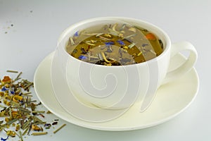 Black tea in glass cup with mint. Tea leaves in wooden spoon. On white, isolated background