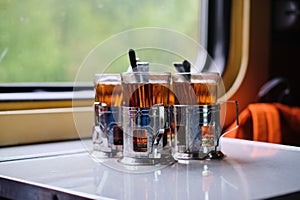 Black tea glasses in cup holders on a table on a train