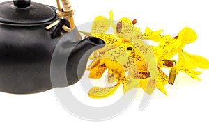 Black tea pot with Mokkara yellow Orchid flower isolated on whit