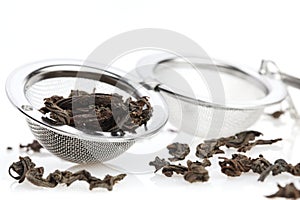 Black tea, and tea strainer with chain, isolated on a white background.