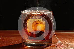 Black tea with tea bag in glass and with steam Vapour - macro view with black background