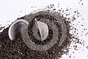 Black tea and tea strainer on white background.