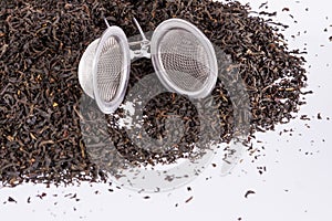 Black tea and tea strainer on white background.