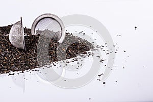 Black tea and tea strainer on white background.