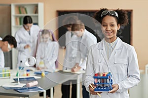 Black teen schoolgirl wearing lab coat in science class smiling at camera