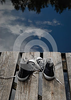 Black teenager's shoes standing on the bridge edge, choice concept