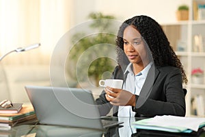 Black tele worker drinking and working at home photo