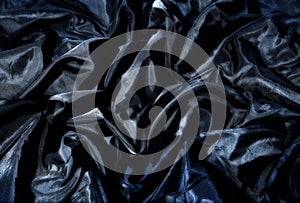 Black textile fabric with creases and blue shine photo