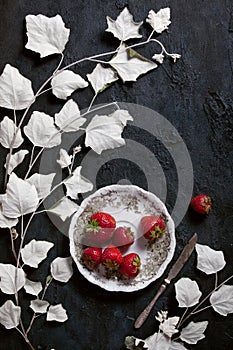 Black textured slate plate with ornate plate and strawberry, food background with copyspace