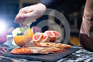 Black Tiger Shrimps. Chef hand squeezing lemon juice dribbling out of fruit. Roasted prawns with herbs. Grilled seafood