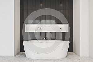 Black tile wall with accent niche and oval bathtub in modern bathroom