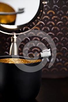 A black toothbrush is reflected in the gold mirror