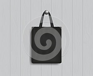 Black tote on wood wall. Mockup of eco canvas bag with handle. Cotton fabric tote. Reusable cloth of ecobag for shopping, grocery