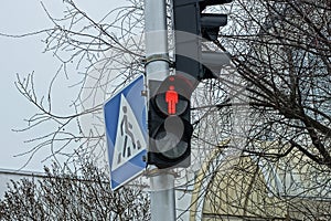 Black traffic light with a red glowing stop lamp on a metal pole