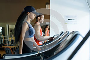 Black trainer and african american woman on the treadmill in gym. Fitness concept
