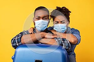 Black Travelers Couple Wearing Masks Posing With Suitcase In Studio