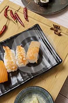 Black tray with Norwegian salmon nigiri sushi and spicy cooked prawns