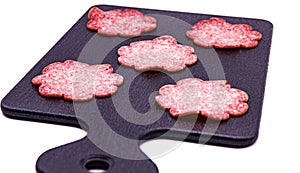 a black tray with six pink cookies on it and a black spatula with four pink cookies on it